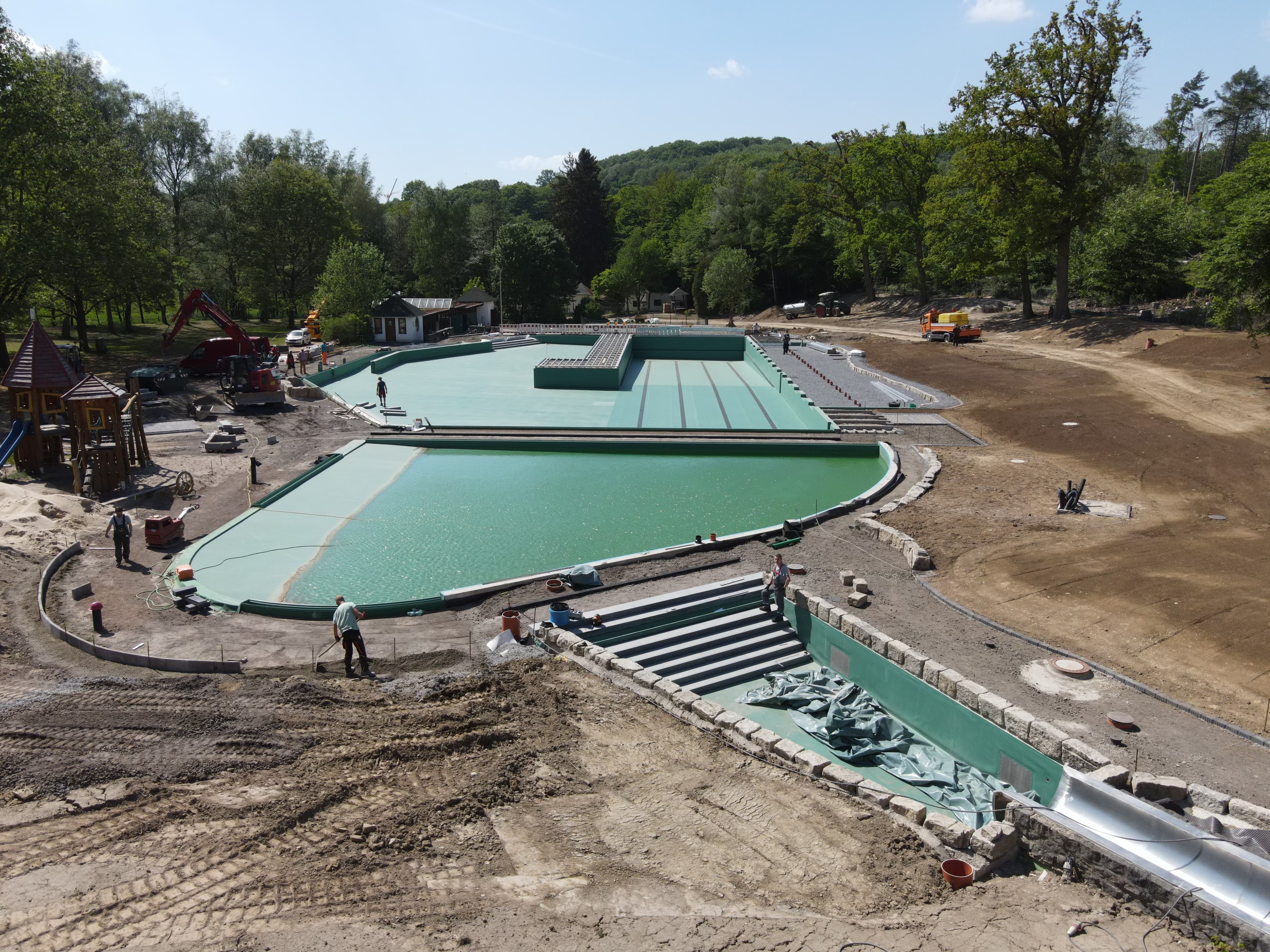 Freibad-Komplex mit mehreren Becken während der Abdichtungs- und Sanierungsarbeiten, Luftaufnahme